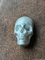 front view of skull pewter ingot on brown surface