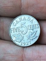 Reverse side of 1927 Canada 5 cent coin showing denomination and maple leaves
