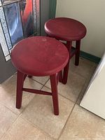 Both red wooden stools side by side showing overall form
