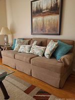 Front view of beige fabric sofa with five pillows placed along back