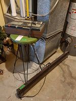 Cassette deck on metal stool beside long room heater in workshop setting