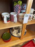 Overall view of mugs on upper shelf and bowls on lower shelf within cabinet