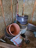 Stack of assorted planters and hanging baskets in shed corner