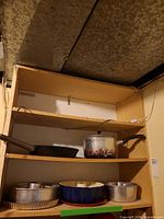 Cabinet shelves with skillet, saucepan with lid, bundt pan, multiple round cake pans