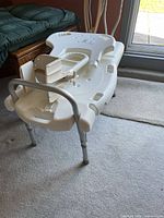 White plastic bath transfer bench upside down showing seat, backrest, armrest and aluminum legs