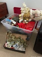 Large plastic bin holding Santa figure, ribbons, greenery, cups in shoe box