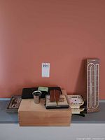 Lot overview showing wooden box, cribbage board, coaster boxes, metal cup, card cases