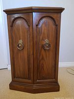 front view of medium brown wood cabinet with double doors and brass ring pulls