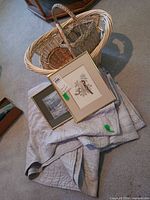 Overall lot showing quilt, two framed prints and three nested wicker baskets