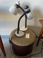 Two desk lamps on top of cylindrical ottoman