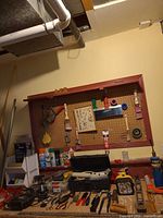 Workbench with pegboard showing assorted hand tools, toolbox and parts bins