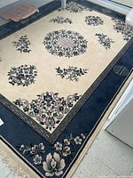 Full view of rectangular ivory and navy area rug on floor