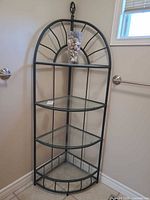 Full view of metal and glass corner etagere with vase displayed on top shelf