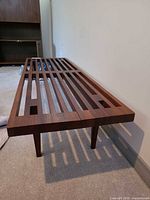 Full view of teak slatted bench angled from side