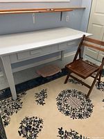 Table and folding chair together on rug, drawers visible