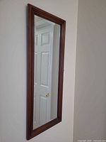 Full view of rectangular wood-framed mirror hung vertically
