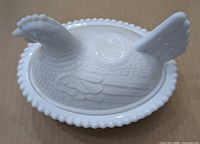 Side view of milk glass hen on nest covered dish showing beaded rim and molded feather detail