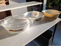 Three casserole dishes and one lid displayed on shelf