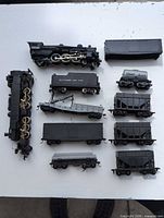 Group shot of locomotive parts, tender and nine freight cars