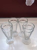 Four clear ribbed glass sundae glasses standing upright