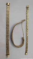 Three gold-plated link bracelets side by side showing overall designs and clasps