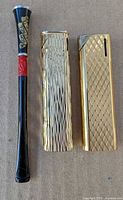 Group shot of cigarette holder and two gold lighters