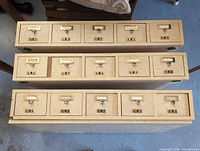 Top view of three stacked cabinet sections showing 15 drawers with brass hardware