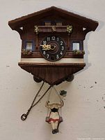Full view of chalet cuckoo clock with weights and figurine