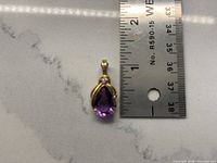 Front view of pendant beside ruler showing overall size