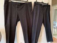 Both pairs of black pants hanging to show overall look