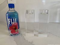 Pair of crystal tea light holders beside Fiji bottle for scale
