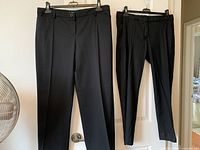 Both pairs of black dress pants hanging on door, full view