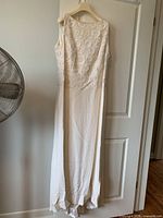 Full view of ivory Escada sleeveless gown hanging on door