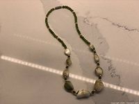 Full view of jade nugget and bead necklace on surface