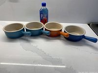 four Le Creuset handled soup bowls with FIJI bottle for scale