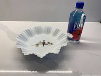 Top view of scalloped bowl beside water bottle for scale