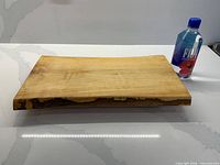 Top view of rectangular live edge wooden serving board beside water bottle for scale