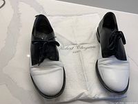Pair of black and white Robert Clergerie oxford shoes on dust bag