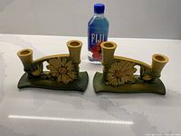 Front view of both Roseville double candleholders alongside water bottle for scale