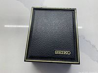 Closed Seiko black textured presentation box with gold logo