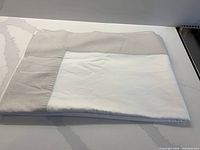 Folded two-tone linen tablecloth showing beige border and white center
