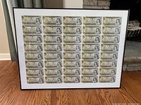 Full view of framed uncut sheet showing 5×6 layout of $1 notes.
