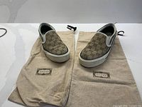 Top view of both Gucci slip-on sneakers on dust bags