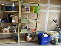 Overall view of garage shelving showing extension cord reel, Prestone coolant jug, windshield washer fluid, storage bins, metal pail, cooler, hardware boxes and lawn edger