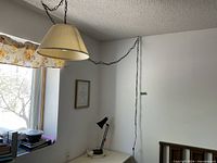 Overall view of beige/cream pleated fabric pendant lamp hanging from ceiling with metal chain and cord