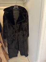 Front view of dark brown real fur coat on hanger