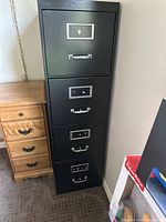 Front view of black four-drawer metal filing cabinet with handles and label frames