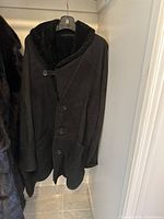 front view of black shearling coat on hanger