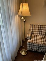 Full view of floor lamp beside chair showing shade, adjustable arm, porcelain accent and overall height