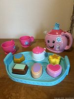 Full set displayed: teapot, tray, cups, sugar bowl, pastries